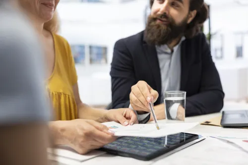 Casal a analisar despesas em casa com documentos e portátil, representando a revisão do crédito habitação para reduzir a prestação mensal.